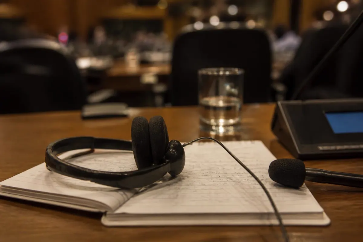 An interpreter's headset and microphone resting on a notepad in a meeting room